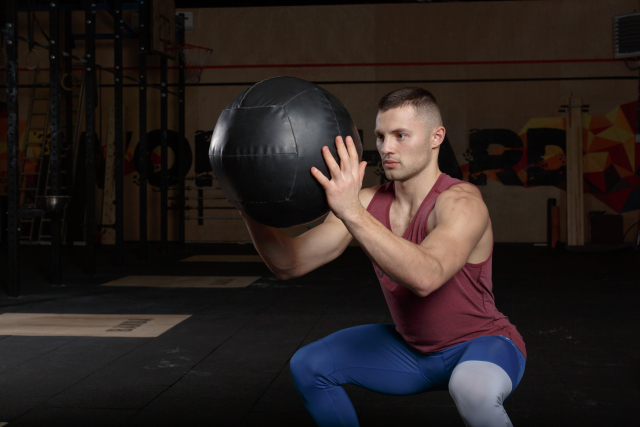 メディシンボールを持ってスクワットをする男性
